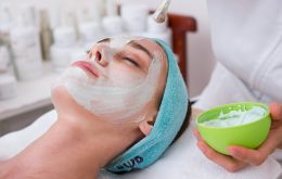 woman lying on blue towel with white cream on face